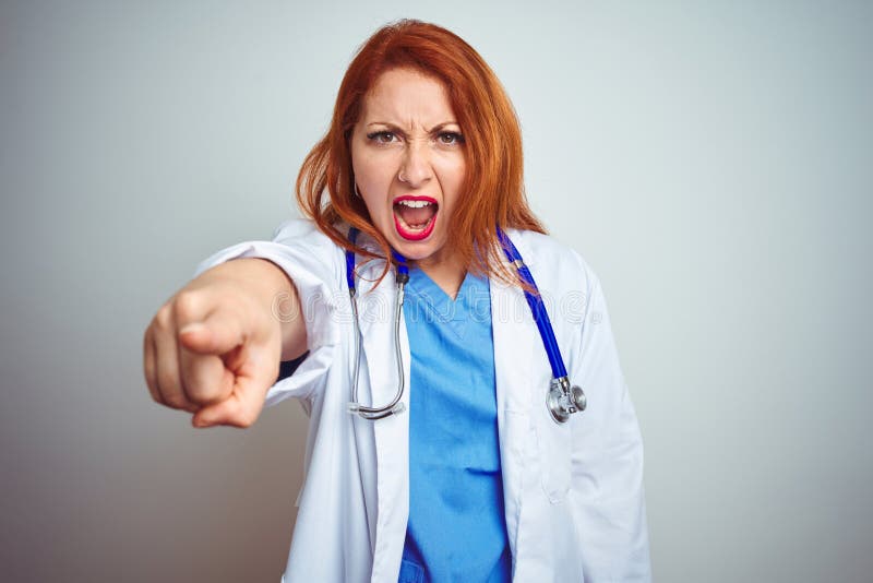Young redhead doctor woman using stethoscope over white isolated background pointing displeased and frustrated to the camera, angry and furious with you. Young redhead doctor woman using stethoscope over white isolated background pointing displeased and frustrated to the camera, angry and furious with you