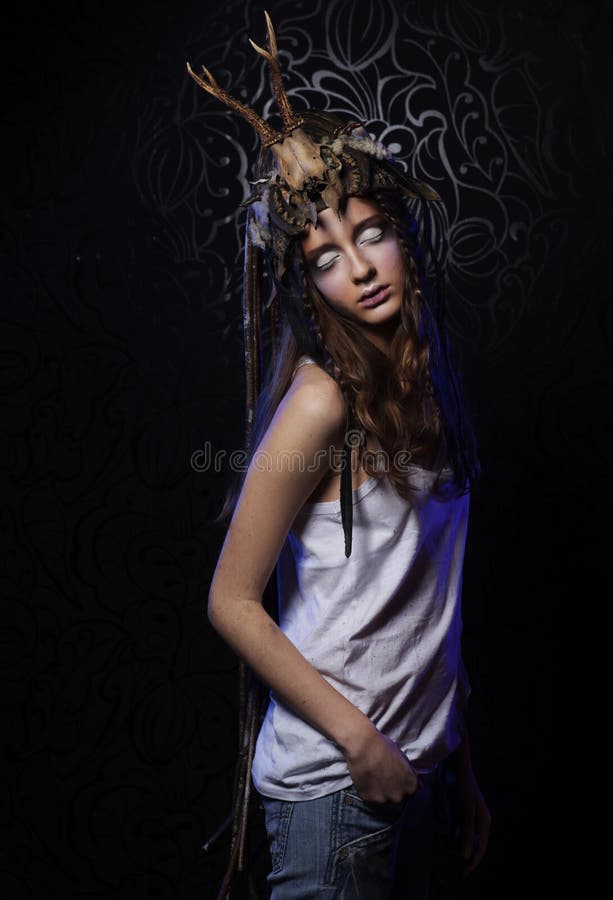 Young female model with bright makeup, braids and a skull on her head over black background. Young female model with bright makeup, braids and a skull on her head over black background