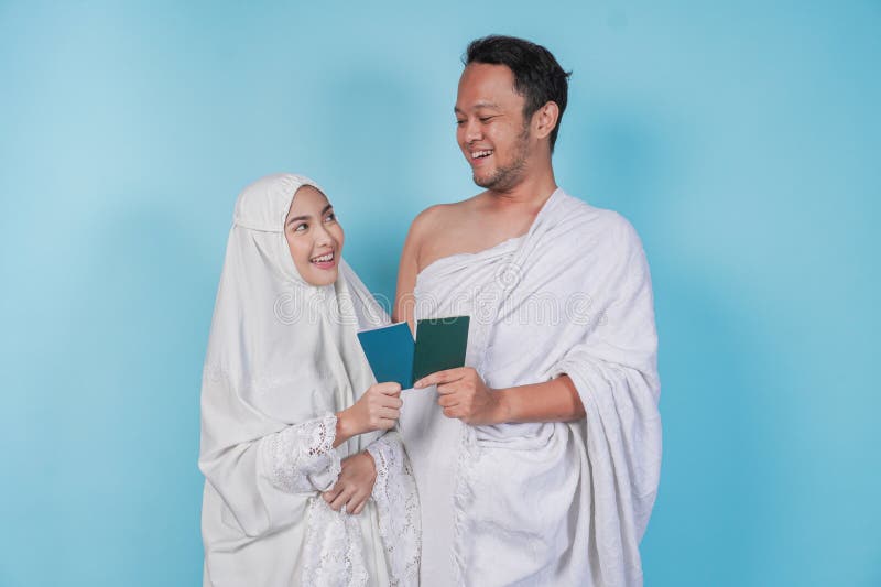 νεαρό μουσουλμάνο ασιάτισσα ζευγάρι στο ihram και φορεμένη προσευχή κρατώντας διαβατήριο, ενώ κοιτούν το ένα το άλλο απομονωμένο α στοκ φωτογραφίες