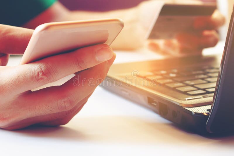 Νεαρός άνδρας χρησιμοποιώντας το smartphone και κρατώντας την πιστωτική κάρτα με το lap-top φ στοκ φωτογραφίες Νεαρός άνδρας χρησιμοποιώντας το smartphone και κρατώντας την πιστωτική κάρτα με το lap-top φ στοκ φωτογραφίες