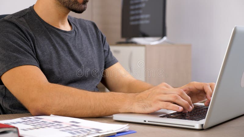 Νεαρός άνδρας που εργάζεται με το lap-top στην επιχειρησιακή τεκμηρίωσή του στοκ φωτογραφία με δικαίωμα ελεύθερης χρήσης Νεαρός άνδρας που εργάζεται με το lap-top στην επιχειρησιακή τεκμηρίωσή του στοκ φωτογραφία με δικαίωμα ελεύθερης χρήσης