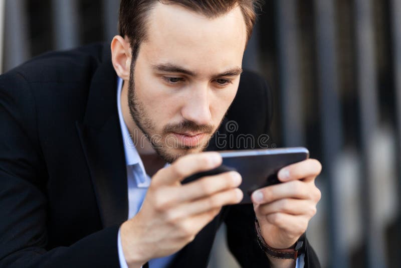 νεαρός επιχειρηματίας ψάχνει για παιχνίδι smartphone. εξάρτηση πληροφοριών στοκ φωτογραφία με δικαίωμα ελεύθερης χρήσης
