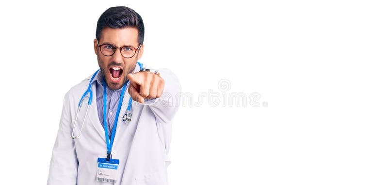 Young hispanic man wearing doctor uniform and stethoscope pointing displeased and frustrated to the camera, angry and furious with you. Young hispanic man wearing doctor uniform and stethoscope pointing displeased and frustrated to the camera, angry and furious with you