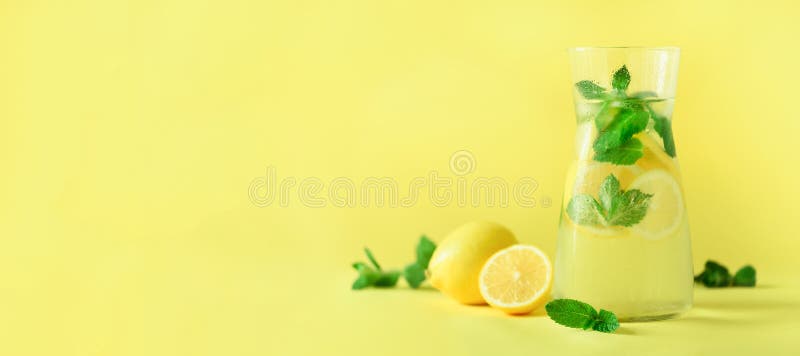 Detox water with mint, lemon on yellow background. Banner with copy space. Citrus lemonade. Summer fruit infused water. Detox water with mint, lemon on yellow background. Banner with copy space. Citrus lemonade. Summer fruit infused water