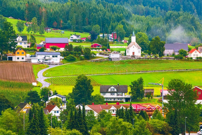 Norwegian village landscape with meadows, mountains, church and colorful houses. Loen, Norway. Norwegian village landscape with meadows, mountains, church and colorful houses. Loen, Norway