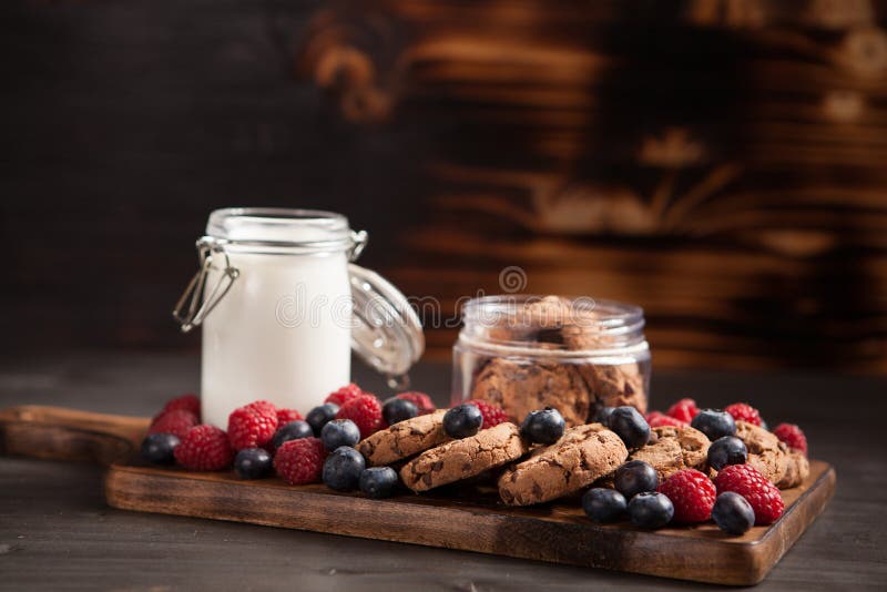 Νόστιμα oatmeal σοκολάτας μπισκότα στη γραμμή πέρα από ένα ξύλινο πιάτο με το φρέσκο γάλα στοκ φωτογραφίες Νόστιμα oatmeal σοκολάτας μπισκότα στη γραμμή πέρα από ένα ξύλινο πιάτο με το φρέσκο γάλα στοκ φωτογραφίες