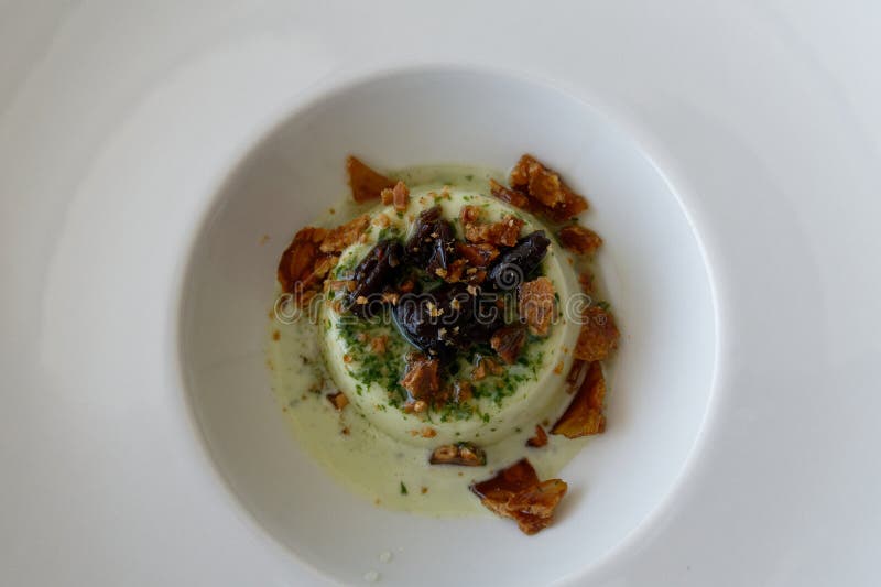 νόστιμο ιταλικό επιδόρπιο που ονομάζεται panna cotta αρωματισμένο με σάλτσα πέστο που έχει γευτεί με καραμέλες και ελιές ταγκιάσκα στοκ εικόνα