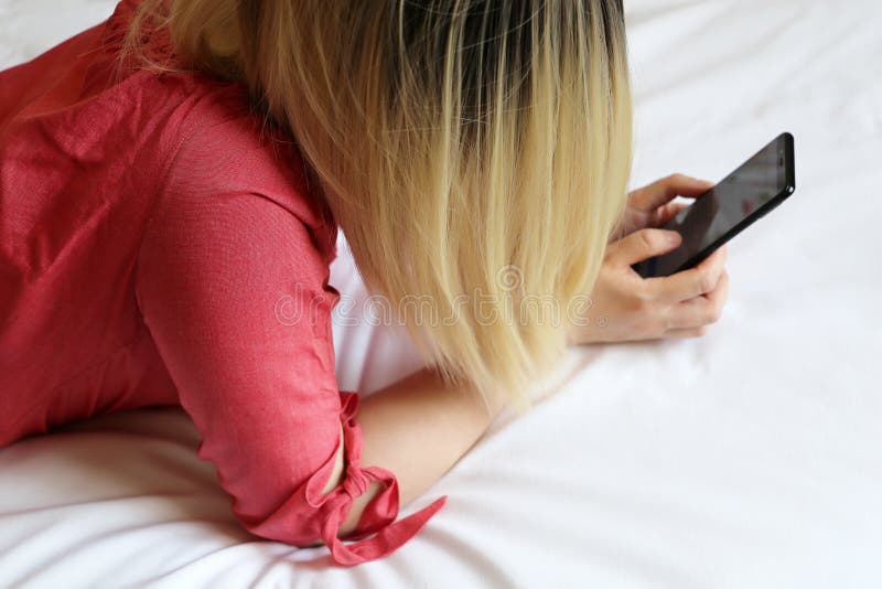 Ξανθή γυναίκα με το smartphone που βάζει στο κρεβάτι, κορίτσι που χρησιμοποιεί το κινητό τηλέφωνο στο σπίτι στοκ εικόνες Ξανθή γυναίκα με το smartphone που βάζει στο κρεβάτι, κορίτσι που χρησιμοποιεί το κινητό τηλέφωνο στο σπίτι στοκ εικόνες