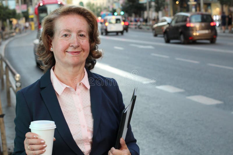 Ξανθή χαμογελώντας επιχειρηματίας που κρατά το μίας χρήσης φλυτζάνι στην πολυάσχολη οδό πόλεων με το διάστημα αντιγράφων στοκ φωτογραφία Ξανθή χαμογελώντας επιχειρηματίας που κρατά το μίας χρήσης φλυτζάνι στην πολυάσχολη οδό πόλεων με το διάστημα αντιγράφων στοκ φωτογραφία
