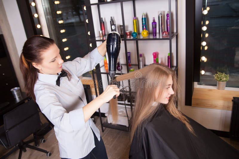 Ξεραίνοντας τρίχα Hairstylist ξανθή στο σαλόνι στοκ φωτογραφίες με δικαίωμα ελεύθερης χρήσης Ξεραίνοντας τρίχα Hairstylist ξανθή στο σαλόνι στοκ φωτογραφίες με δικαίωμα ελεύθερης χρήσης