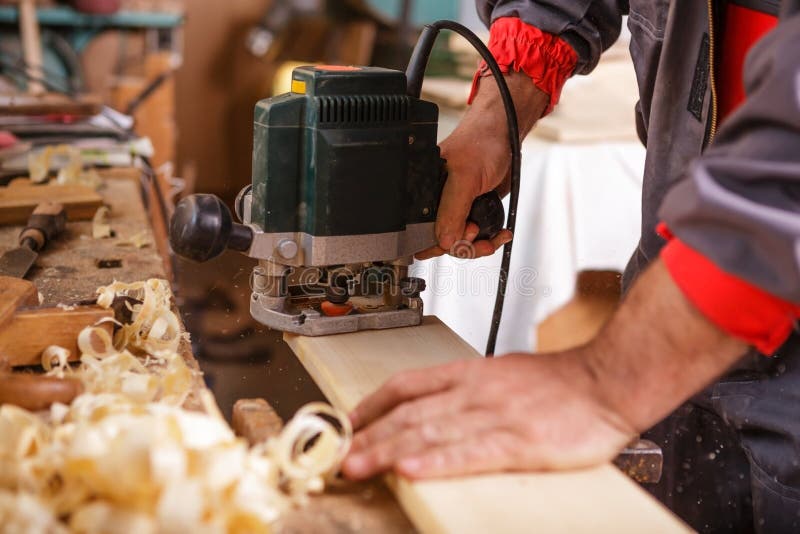 Ξυλουργός στην εργασία με ηλεκτρικό joinery μηχανών πλανίσματος στοκ εικόνα Ξυλουργός στην εργασία με ηλεκτρικό joinery μηχανών πλανίσματος στοκ εικόνα