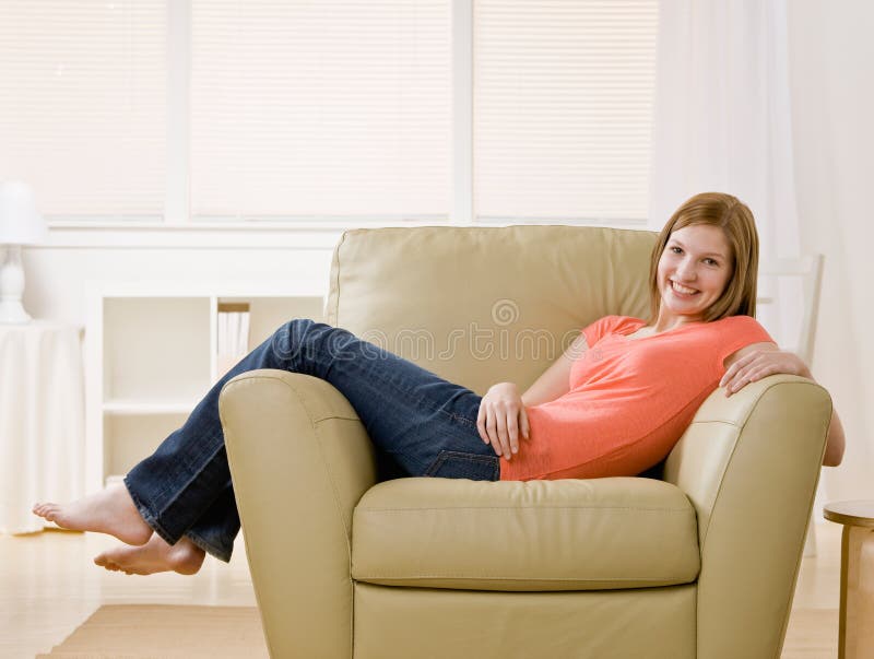 Casual barefoot young woman lounging on armchair at home. Casual barefoot young woman lounging on armchair at home
