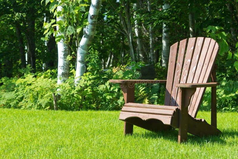 Ξύλινη καρέκλα θερινών χορτοταπήτων Adirondack έξω στην πράσινη χλόη στοκ εικόνα Ξύλινη καρέκλα θερινών χορτοταπήτων Adirondack έξω στην πράσινη χλόη στοκ εικόνα