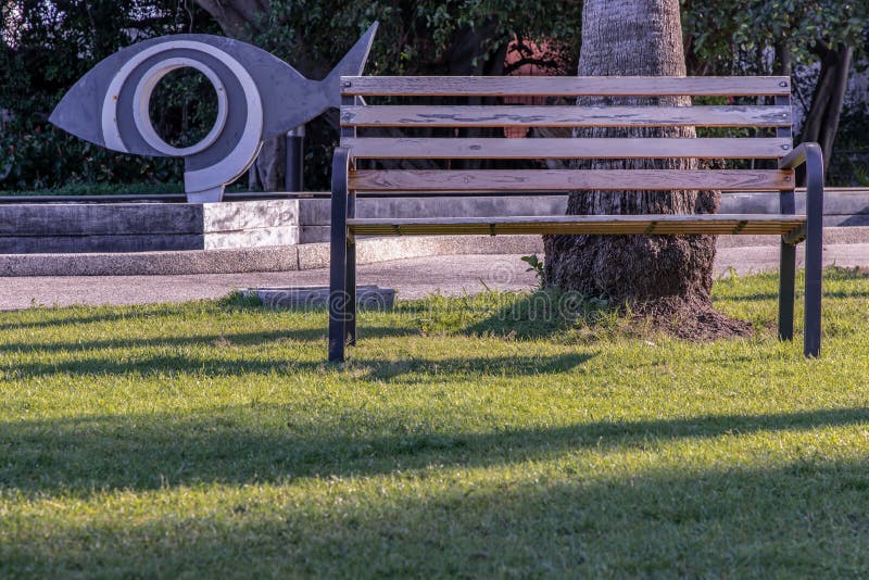 ξύλινες πάγκοι στο γρασίδι σε μια σκοτεινή περιοχή του πάρκου στοκ εικόνα
