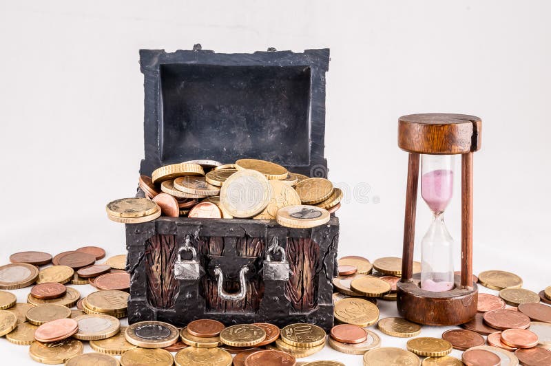 A wooden chest full of coins and a sand timer, real image. A wooden chest full of coins and a sand timer, real image