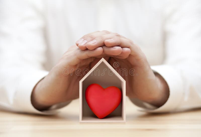 Small wooden house with red heart protected by hands. Small wooden house with red heart protected by hands