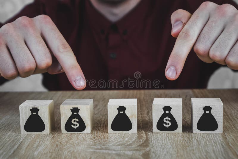 5 ξύλινους κύβους υπό μορφή σακουλών με χρήματα Το χέρι επιλέγει μια τσάντα στοκ φωτογραφία 5 ξύλινους κύβους υπό μορφή σακουλών με χρήματα Το χέρι επιλέγει μια τσάντα στοκ φωτογραφία