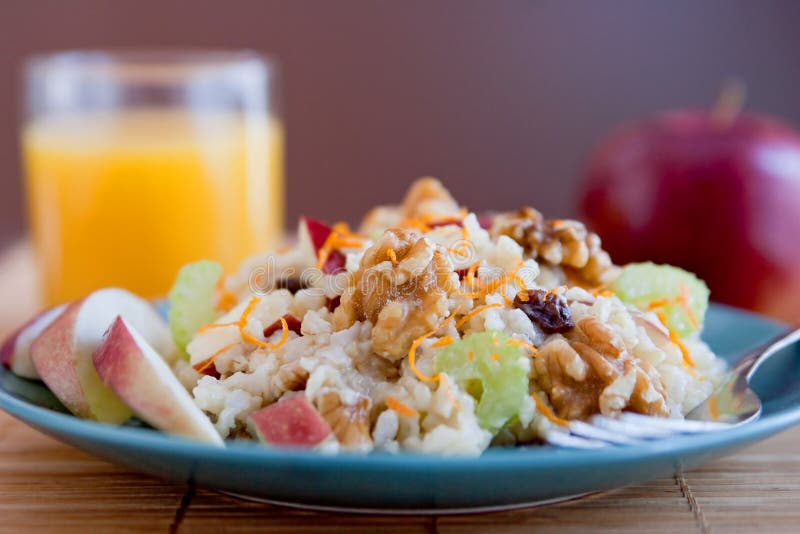 One plate of apple walnut salad similar to Waldorf Salad on a blue plate with a glass of orange juice. One plate of apple walnut salad similar to Waldorf Salad on a blue plate with a glass of orange juice