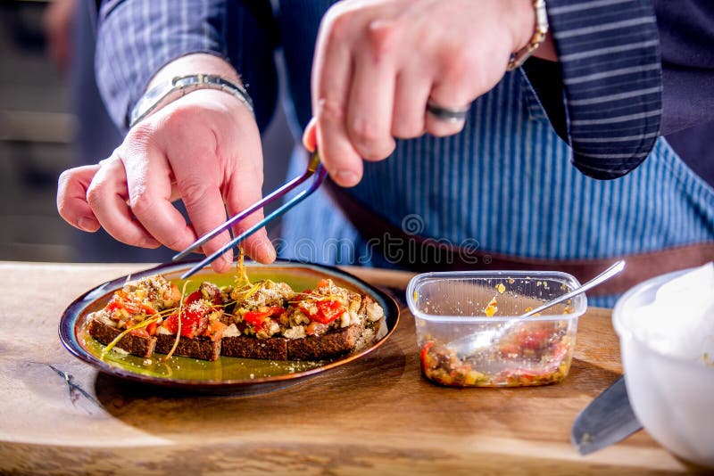 Ο αρχιμάγειρας διακοσμεί τα vegan σάντουιτς με τα ψημένα λαχανικά και το τυρί στο τηγανισμένο ψωμί τεχνών Κύρια κατηγορία στην κο στοκ εικόνες Ο αρχιμάγειρας διακοσμεί τα vegan σάντουιτς με τα ψημένα λαχανικά και το τυρί στο τηγανισμένο ψωμί τεχνών Κύρια κατηγορία στην κο στοκ εικόνες