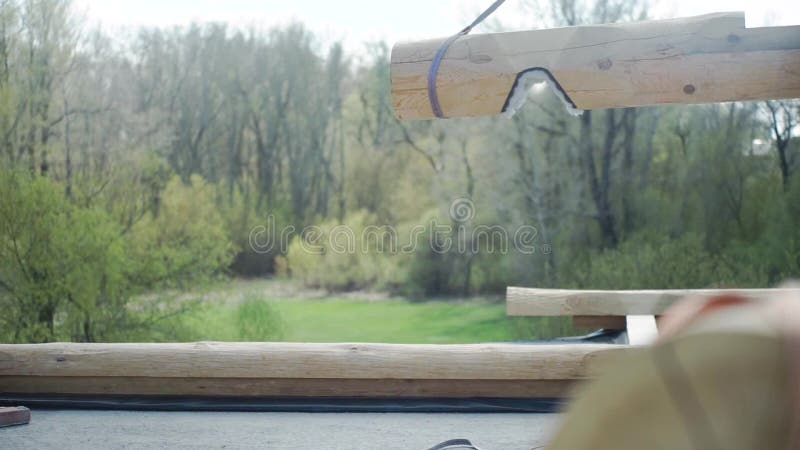 Ο γερανός ανυψώνει το κούτσουρο r Ο γερανός ανυψώνει την ξυλεία για την κατασκευή ενός ξύλινου σπιτιού