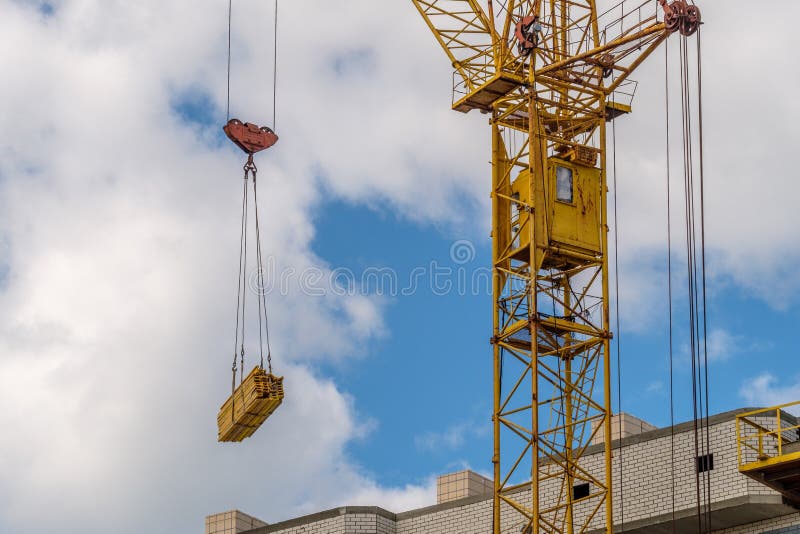 Ο γερανός πύργων κίτρινος παίρνει τα οικοδομικά υλικά στην οικοδόμηση του multi-storey σπιτιού, θερινή ημέρα στοκ φωτογραφία με δικαίωμα ελεύθερης χρήσης Ο γερανός πύργων κίτρινος παίρνει τα οικοδομικά υλικά στην οικοδόμηση του multi-storey σπιτιού, θερινή ημέρα στοκ φωτογραφία με δικαίωμα ελεύθερης χρήσης