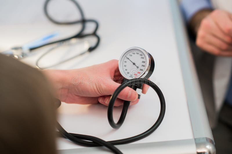 Ο γιατρός μετρά τη πίεση του αίματος με ένα tonometer στοκ εικόνα με δικαίωμα ελεύθερης χρήσης Ο γιατρός μετρά τη πίεση του αίματος με ένα tonometer στοκ εικόνα με δικαίωμα ελεύθερης χρήσης
