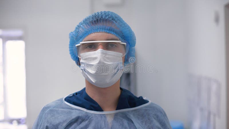 Ο γιατρός νεαρών άνδρων στην ΚΑΠ, τα γυαλιά και τη μάσκα εξετάζει τη κάμερα