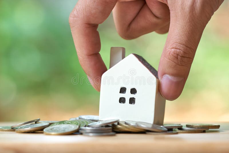Ο επιχειρηματίας που κρατά ένα πρότυπο πρότυπο σπιτιών τοποθετείται σε έναν σωρό των νομισμάτων χρησιμοποίηση ως επιχειρησιακή έν στοκ φωτογραφίες Ο επιχειρηματίας που κρατά ένα πρότυπο πρότυπο σπιτιών τοποθετείται σε έναν σωρό των νομισμάτων χρησιμοποίηση ως επιχειρησιακή έν στοκ φωτογραφίες