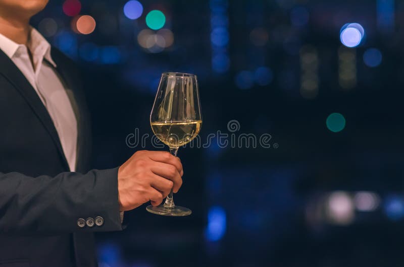 Ο επιχειρηματίας που φορά το μπλε ναυτικό κοστούμι χρώματος στέκεται στο φραγμό στεγών που ψήνει ένα ποτήρι του άσπρου κρασιού με στοκ φωτογραφία με δικαίωμα ελεύθερης χρήσης Ο επιχειρηματίας που φορά το μπλε ναυτικό κοστούμι χρώματος στέκεται στο φραγμό στεγών που ψήνει ένα ποτήρι του άσπρου κρασιού με στοκ φωτογραφία με δικαίωμα ελεύθερης χρήσης