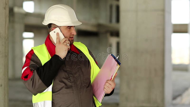ο εργάτης μιλάει σε κινητό τηλέφωνο στην τοποθεσία του έργου απόθεμα βίντεο