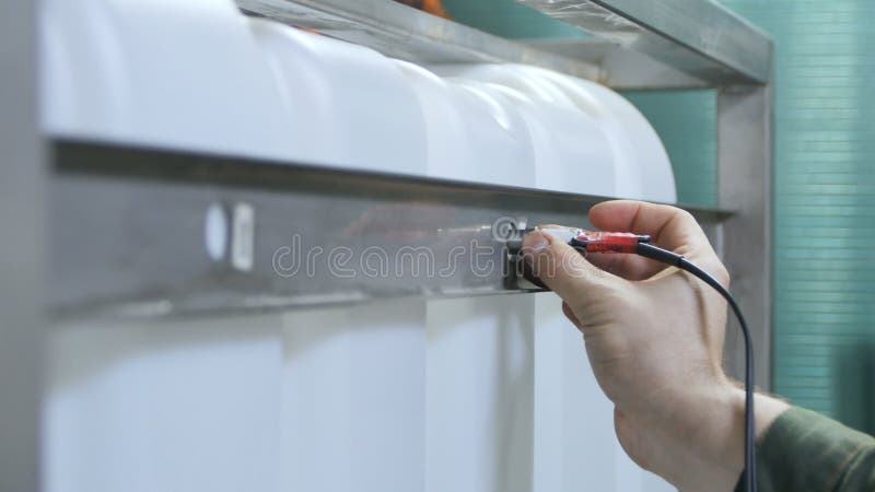 Ο εργαζόμενος πλάγιας όψης ελέγχει το άσπρο ενδιάμεσο μαζικό εμπορευματοκιβώτιο φιλμ μικρού μήκους