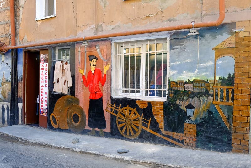 Ο ζωηρόχρωμος καλλιτεχνικά χρωματισμένος τοίχος του παλαιού σπιτιού στο παλαιό μέρος του Tbilisi απεικόνισε τη σκηνή της τοπικής στοκ εικόνες με δικαίωμα ελεύθερης χρήσης