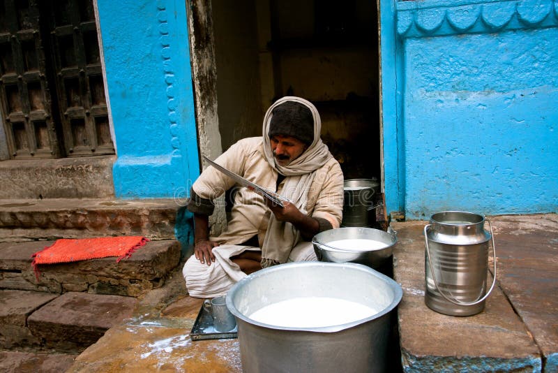 VARANASI, INDIA: Indian milkman sells milk on the street and read a newspaper the same time. Varanasi urban agglomeration had a population of 1,435,113. VARANASI, INDIA: Indian milkman sells milk on the street and read a newspaper the same time. Varanasi urban agglomeration had a population of 1,435,113