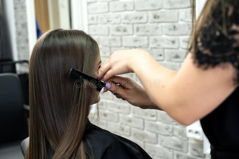 Ο κομμωτής κάνει την ελασματοποίηση τρίχας σε ένα σαλόνι ομορφιάς για ένα κορίτσι με την τρίχα brunette στοκ φωτογραφία με δικαίωμα ελεύθερης χρήσης Ο κομμωτής κάνει την ελασματοποίηση τρίχας σε ένα σαλόνι ομορφιάς για ένα κορίτσι με την τρίχα brunette στοκ φωτογραφία με δικαίωμα ελεύθερης χρήσης