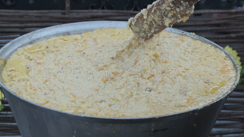 ο μάγειρας προετοιμάζει το ρύζι porridge σε ένα παραδοσιακό μεγάλο καζάνι. φαγητό