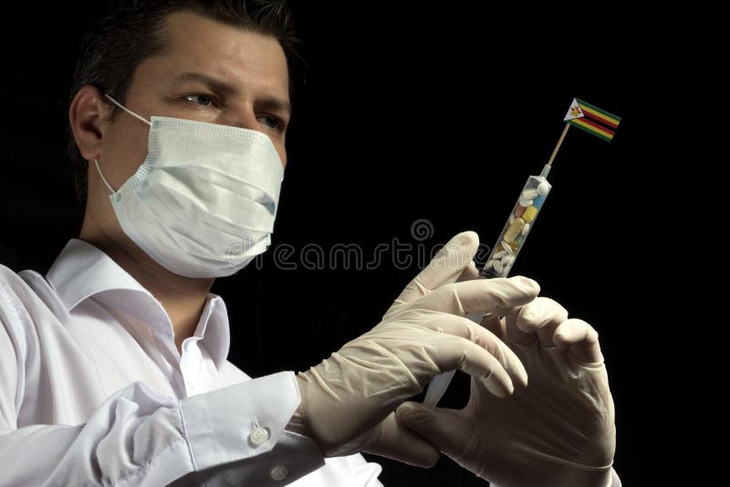 Ο νεαρός άνδρας ως γιατρός δίνει μια ιατρική έγχυση στην της Ζιμπάμπουε σημαία στοκ φωτογραφία