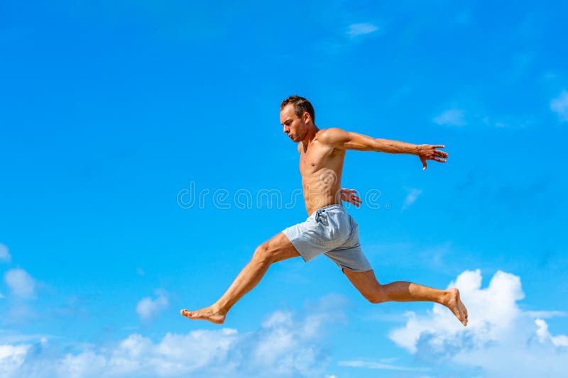 Ο νεαρός άνδρας που κάνει parkour πηδά στο υπόβαθρο μπλε ουρανού την ηλιόλουστη θερινή ημέρα στοκ φωτογραφία με δικαίωμα ελεύθερης χρήσης