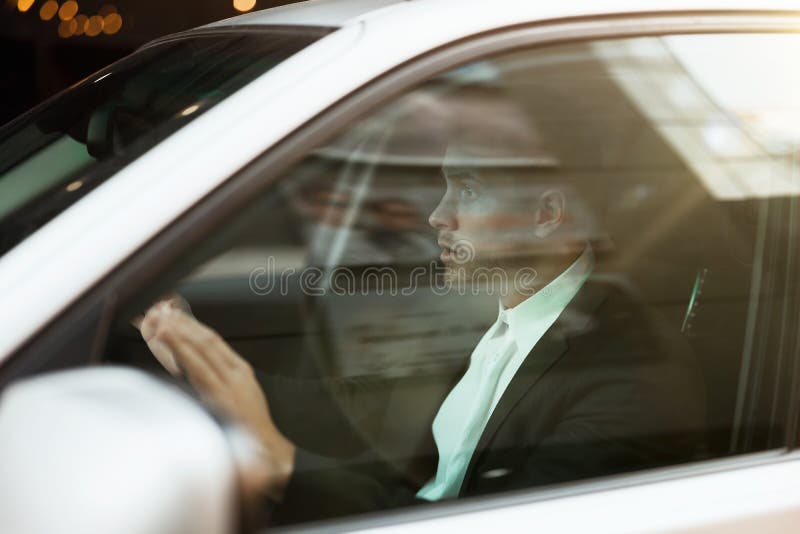ο νεαρός επιχειρηματίας φαίνεται έκπληκτος με τα χέρια στο τιμόνι ενώ οδηγούσε την ιδέα του για την ασφάλεια του αυτοκινήτου στοκ φωτογραφία με δικαίωμα ελεύθερης χρήσης