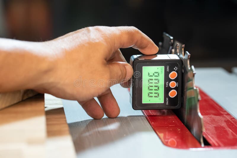 Carpenter use Horizontal Angle Meter or Digital Inclinometer to align blades and fences on tablesaw at workshop,woodworking concept.selective focus. Carpenter use Horizontal Angle Meter or Digital Inclinometer to align blades and fences on tablesaw at workshop,woodworking concept.selective focus