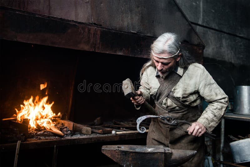 Ο παλαιός σιδηρουργός σφυρηλατεί σφυρηλατεί τα προϊόντα μετάλλων στοκ εικόνες