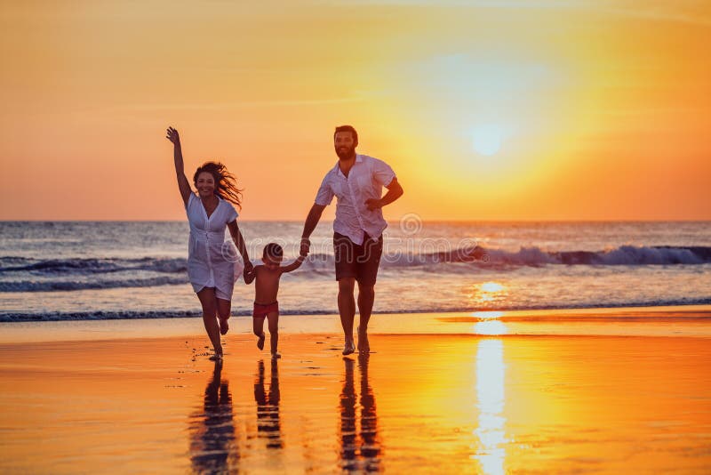 Ο πατέρας, μητέρα, μωρό έχει μια διασκέδαση στην παραλία ηλιοβασιλέματος