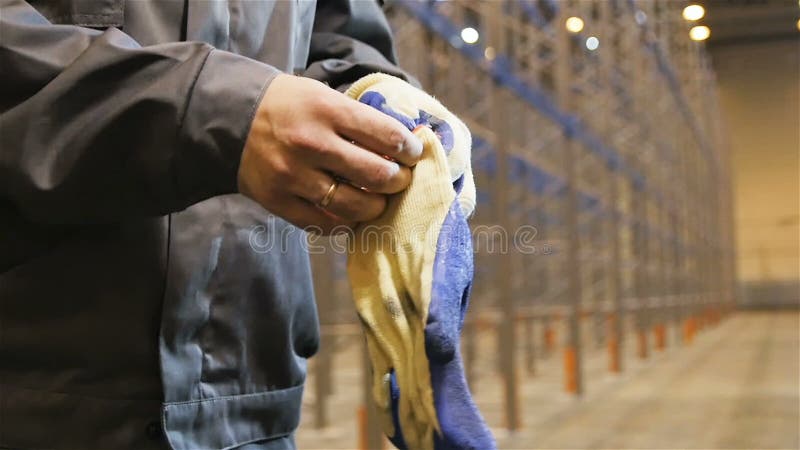 Ο σε αργή κίνηση εργαζόμενος κινηματογραφήσεων σε πρώτο πλάνο σε ομοιόμορφο βάζει στα γάντια απόθεμα βίντεο
