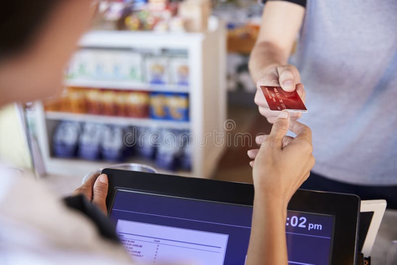Ο ταμίας δέχεται την πληρωμή καρτών από τον πελάτη στις λιχουδιές στοκ φωτογραφίες Ο ταμίας δέχεται την πληρωμή καρτών από τον πελάτη στις λιχουδιές στοκ φωτογραφίες