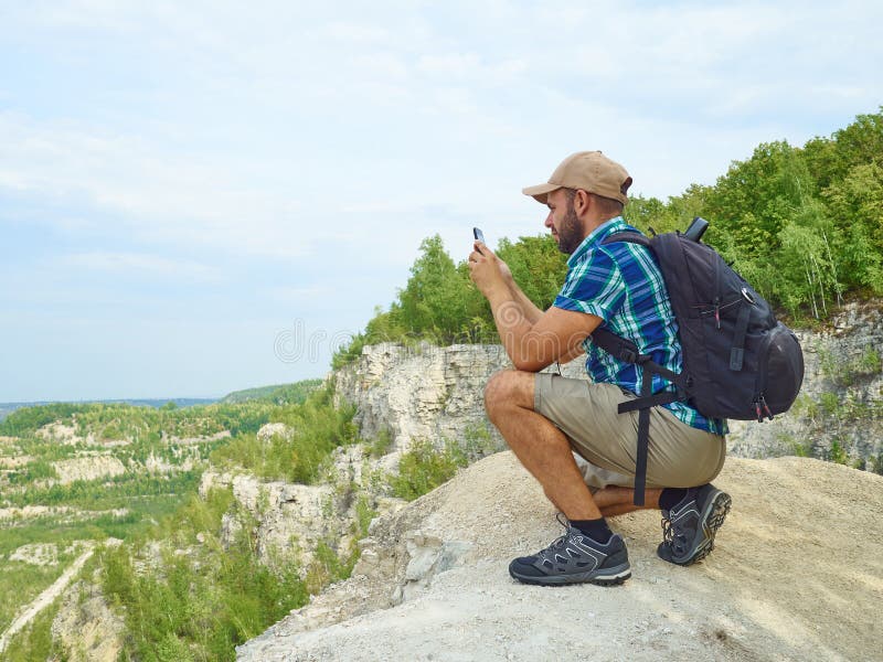 Ο τουρίστας ατόμων χρησιμοποιεί ένα smartphone καθμένος στην άκρη του CLI στοκ εικόνες Ο τουρίστας ατόμων χρησιμοποιεί ένα smartphone καθμένος στην άκρη του CLI στοκ εικόνες