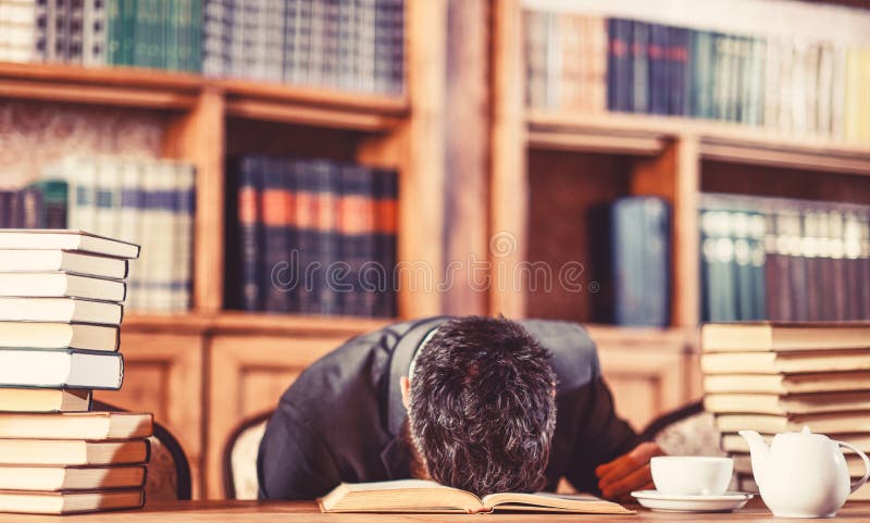 Guy is overworked and sleeps on table. Man sits with head on table with many books. Mature man had too much work. Study, education, hard work, intellectual work, tired, brain, stress concept. Guy is overworked and sleeps on table. Man sits with head on table with many books. Mature man had too much work. Study, education, hard work, intellectual work, tired, brain, stress concept.