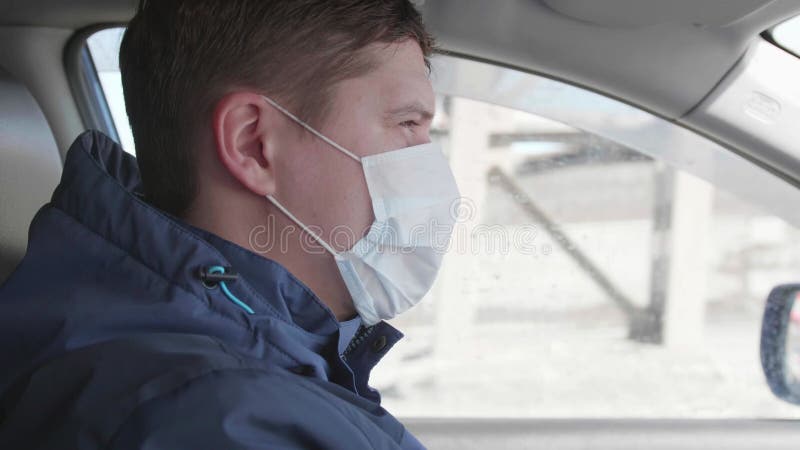 ο τύπος οδηγεί το αυτοκίνητο. ιατρική μάσκα στο πρόσωπο. άτομα χρησιμοποιούν πρόσθετη προστασία κατά των βακτηρίων.