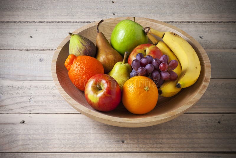 A bowl of fresh whole fruit on a rustic wood background. A bowl of fresh whole fruit on a rustic wood background