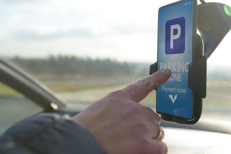 Οδηγός που χρησιμοποιεί το smartphone app για να πληρώσει για το χώρο στάθμευσης στοκ εικόνα με δικαίωμα ελεύθερης χρήσης Οδηγός που χρησιμοποιεί το smartphone app για να πληρώσει για το χώρο στάθμευσης στοκ εικόνα με δικαίωμα ελεύθερης χρήσης