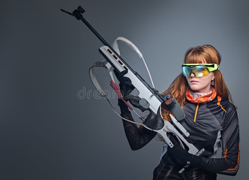 Οι Redhead θηλυκοί αθλητικοί τύποι Biatlon κρατούν το ανταγωνιστικό πυροβόλο όπλο στοκ εικόνες με δικαίωμα ελεύθερης χρήσης Οι Redhead θηλυκοί αθλητικοί τύποι Biatlon κρατούν το ανταγωνιστικό πυροβόλο όπλο στοκ εικόνες με δικαίωμα ελεύθερης χρήσης