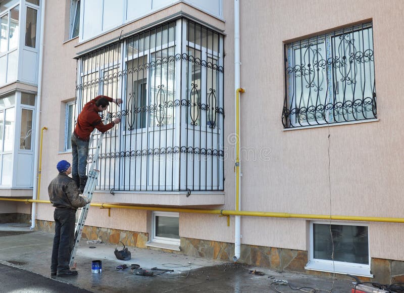 Οι ανάδοχοι εγκαθιστούν τους φραγμούς ασφάλειας σιδήρου παραθύρων στοκ φωτογραφία Οι ανάδοχοι εγκαθιστούν τους φραγμούς ασφάλειας σιδήρου παραθύρων στοκ φωτογραφία